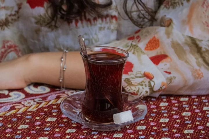 Desenli örtülü masada ince belli çay bardağı
